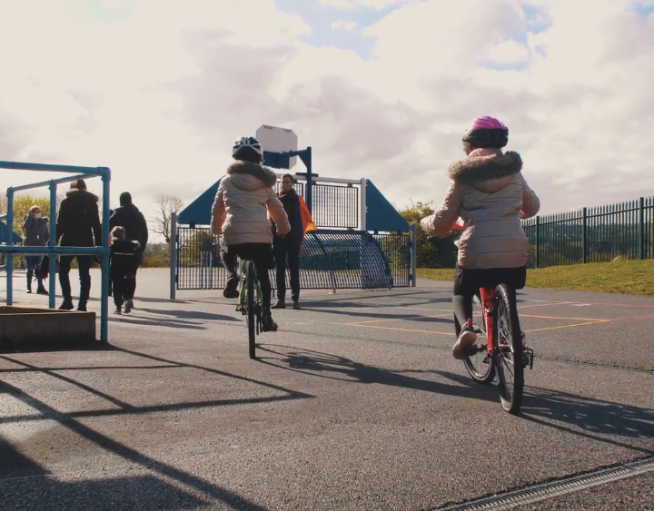 Kids riding bikes towards a playground